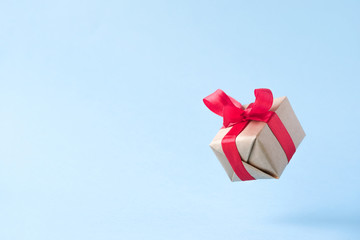 Gift box with red ribbon on blue background. zero gravity. levitation. milimalism. copyspace....