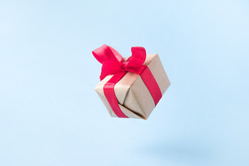 Gift box with red ribbon on blue background. zero gravity. levitation. milimalism. Concept sales, shopping, christmas holidays and birthday