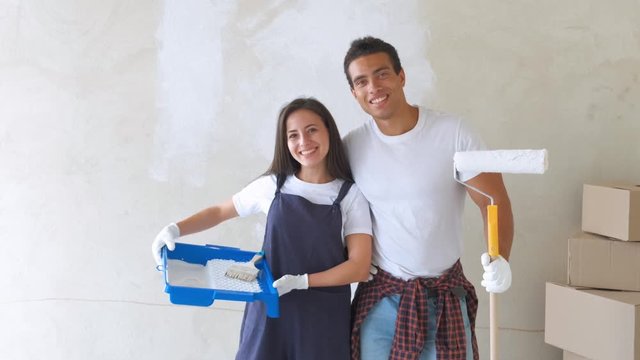 Portrait of a young couple in a new house are painting and decorating the wall of their house