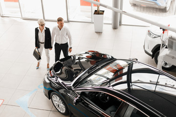 Wife and husband couple in dealership choose a car. Top view