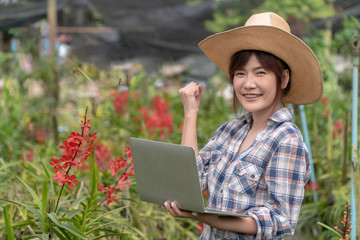 The gardener arranged the orchid garden by holding the notebook and holding the right hand. To...
