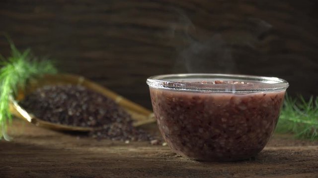 Close up of boiled rice berry in bowl on wooden table. Rice berry on background. Food and healthy concept.