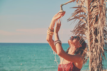 Beautiful woman having a shower on the tropical beach. Summer concept.