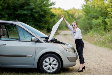 Young woman by the roadside after her car has broken down She opened the hood to see the damage
