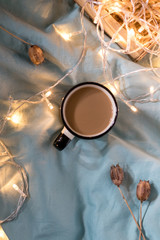 Coffee cup and garland on a bed. Atmospheric swedish hygge style. Cozy winter or autumn morning
