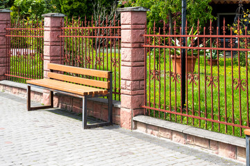 wooden seats along the metal fence in an urban environment