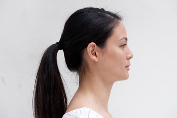 Close up horizontal side portrait of young woman with ponytail against white background