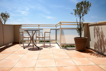 A terrace with table and chairs in a blue sky and ocean view.