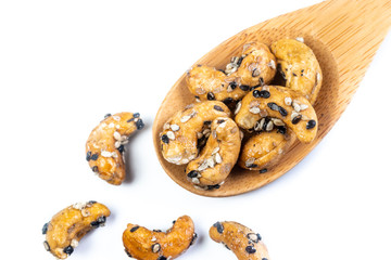 Sesame Coated Cashew Nuts on wooden spoon. Isolated on white background