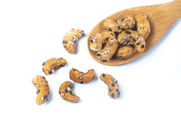 Sesame Coated Cashew Nuts on wooden spoon. Isolated on white background