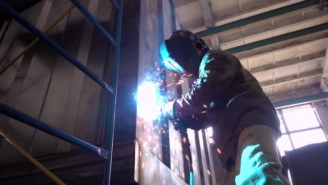 Worker at the factory to weld the iron container with a semi-automatic welding machine