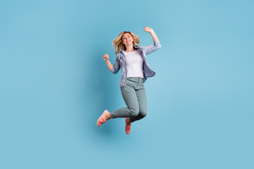 Fototapeta na wymiar Full size photo of cute pretty woman jumping raising fists wearing pants trousers isolated over blue background