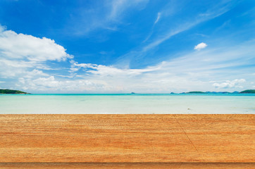 Fototapeta premium wood table with tropical beach and sea summer and blue sky with cloud background. beautiful floor copy space for design your products brand for ad.