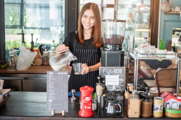 Beautiful barista is smiling  in her coffee shop