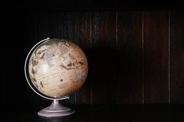 Vintage retro classic school globe model of Earth on dark wood background