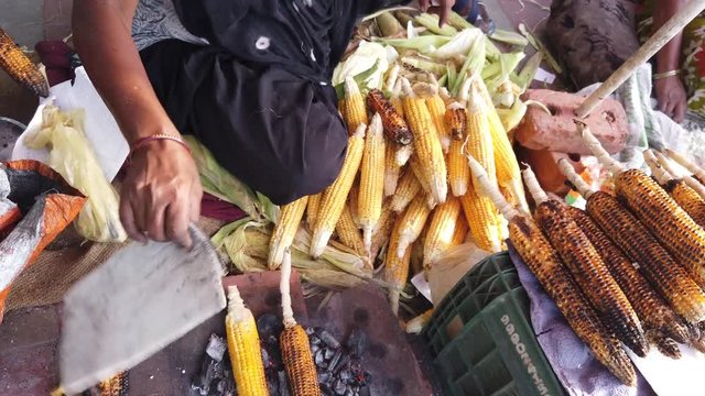 Corn on the cob, slow roasted over hot coals, with squeeze juicy lime wedges and sprinkle salt, cayenne pepper, spicy masala chaat. Popular street food in Southeast Asia. 4k 60fps handheld close-up