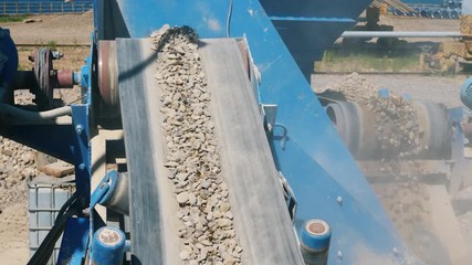 Mining industry concept. Crushing machine moves big stones on a conveyor.