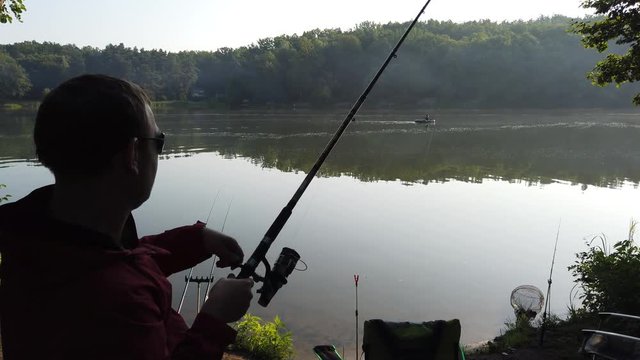 Fishing on the forest lake. A man was fishing on a spinning. The guy pulls the fish out of the lake. Fish on the hook.