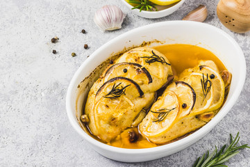 Lemon rosemary chicken breasts in a baking dish. Selective focus, space for text.