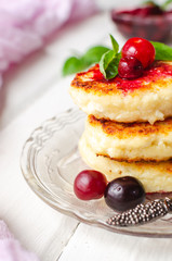 Cottage cheese pancakes on a dark background. Syrniki with fresh mint. Pancakes with cottage cheese on a lilac plate . Homemade food.