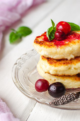 Cottage cheese pancakes on a dark background. Syrniki with fresh mint. Pancakes with cottage cheese on a lilac plate . Homemade food.