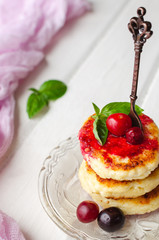 Cottage cheese pancakes on a dark background. Syrniki with fresh mint. Pancakes with cottage cheese on a lilac plate . Homemade food.