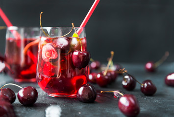 2 cups cherry juice with fresh cherry berries on black background