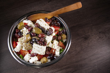 Close-up of delicious gourmet tomato and olives feta cheese salad sprinkled with herbs spices in a metal bowl. The concept of delicious and healthy vegetarian food and body detoxification