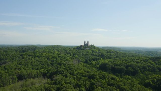 Aerial flight over dense woodlands towards Holy Hill Cathedral and Monastery a prominent landmark and historic site in Wisconsin, USA