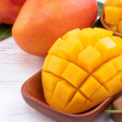 Fresh chopped mango on a tray and bright rustic wooden background. Tropical summer fruit design...