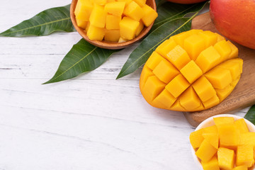Fresh chopped mango on a tray and bright rustic wooden background. Tropical summer fruit design concept, close up, macro, copy space.