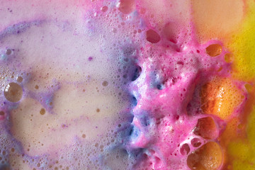 Foam of bath bomb close-up colorful top view background