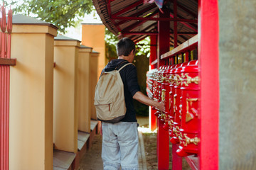 Fototapeta na wymiar Man tourist with backpack turns the prayer drum, asian culture , Buddhism