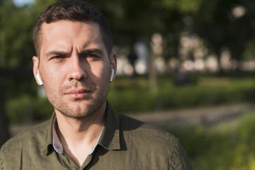 Portrait of serious man wearing wireless earphone looking at camera