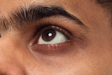 Close up portrait of young hindoo man's face with brown eyes looking up or at side. Human emotions,...