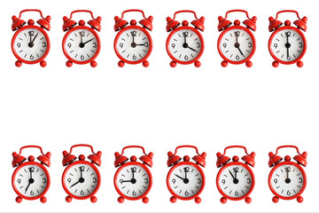 Twelve red metal alarm clocks isolated on a white background. Clocks are showing every hour of the...
