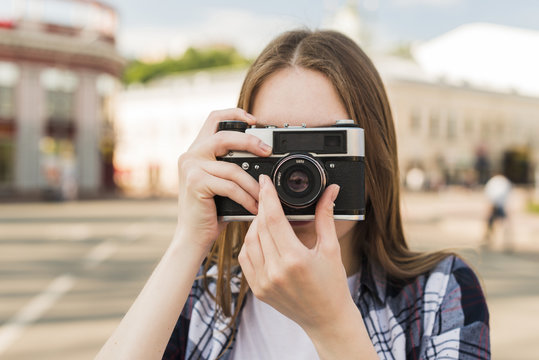 Portrait of young woman taking photograph with camera