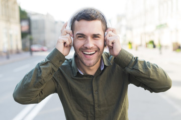 Happy man wearing headphone listening music and looking at camera