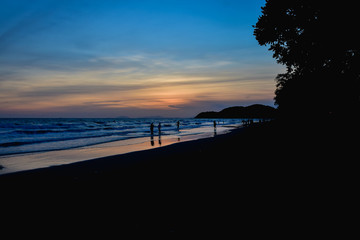 Silhouette of people on great sunset with beautiful view of sea and beach at twilight.