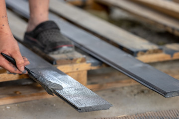 Painting boards with a brush held in hand. Gray, anthracite wood paint.