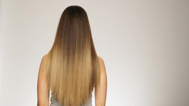 Female model shows her long healthy blonde hair back view slow motion