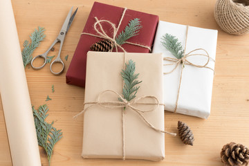 Christmas gifts on a wooden table with twine, scissors and wrapping paper.