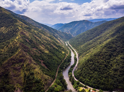 Aerial view of river through forest and mountains, cloudy sky. Ibar river in Serbia