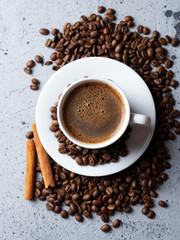 Close-up of white espresso coffee Cup , scattered roasted coffee beans and cinnamon