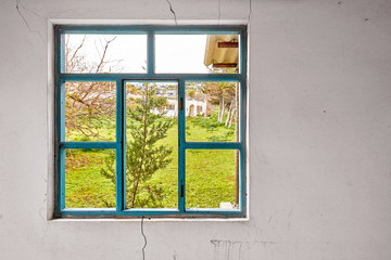 Interior of a ruined house with old, dirty and cracked white wall and a broken window frame with a...
