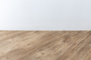 perspective view of empty interior room with white cement wall and brown wooden herringbone floor.