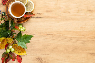Flatlay composition with mug of tea and autumn fallen leaves. Cozy home, autumn desk table concept. Flat lay, top view, copy space.