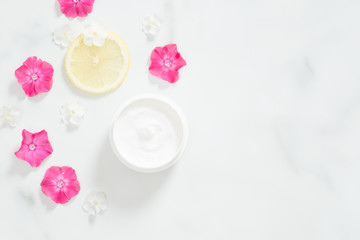Top view of cosmetic lotion with pink flower petals and citrus lemon. Flatlay skin care beauty treatment with jar of body moisturizer. Organic cosmetic products, natural moisturizing cream concept.