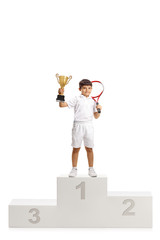 Boy first place tennis winner with a trophy cup standing on a winner's pedestal