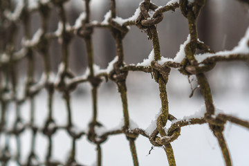 Closeup of an old knitted net covered in snow